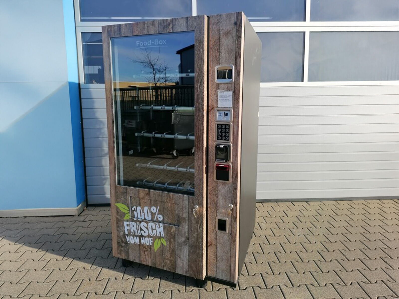 Hofautomat in Holzoptik mit Lebensmitteln und Snacks hinter Glasfront      